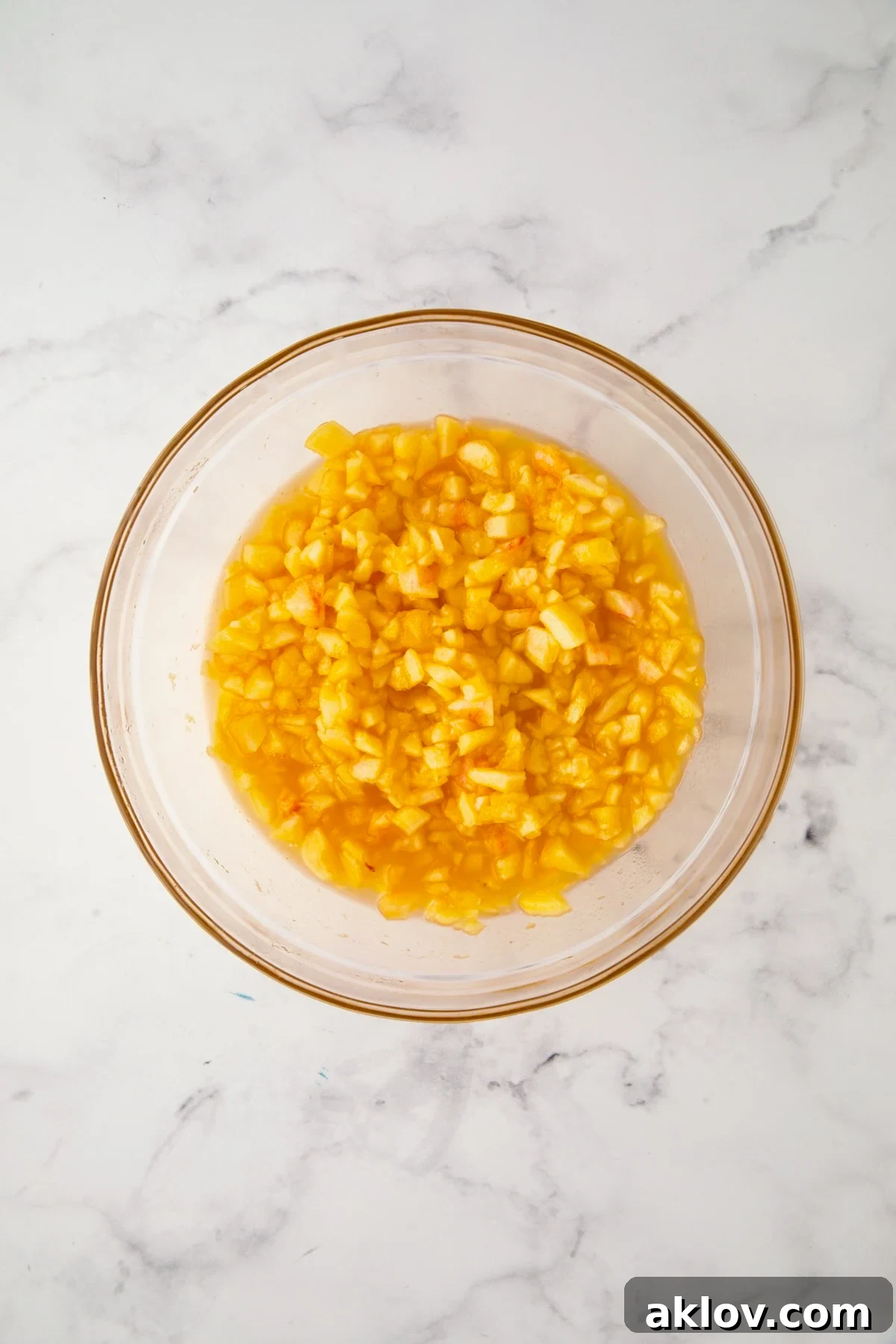 Coarsely chopped peach pieces in a glass bowl with reserved club soda.
