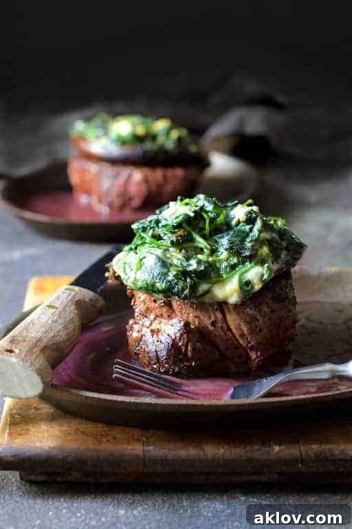 Close-up photo of Beef Tenderloin Fillets with Spinach Cambozola Stuffed Mushrooms and Red Wine Sauce on plate with steak knife on the side.