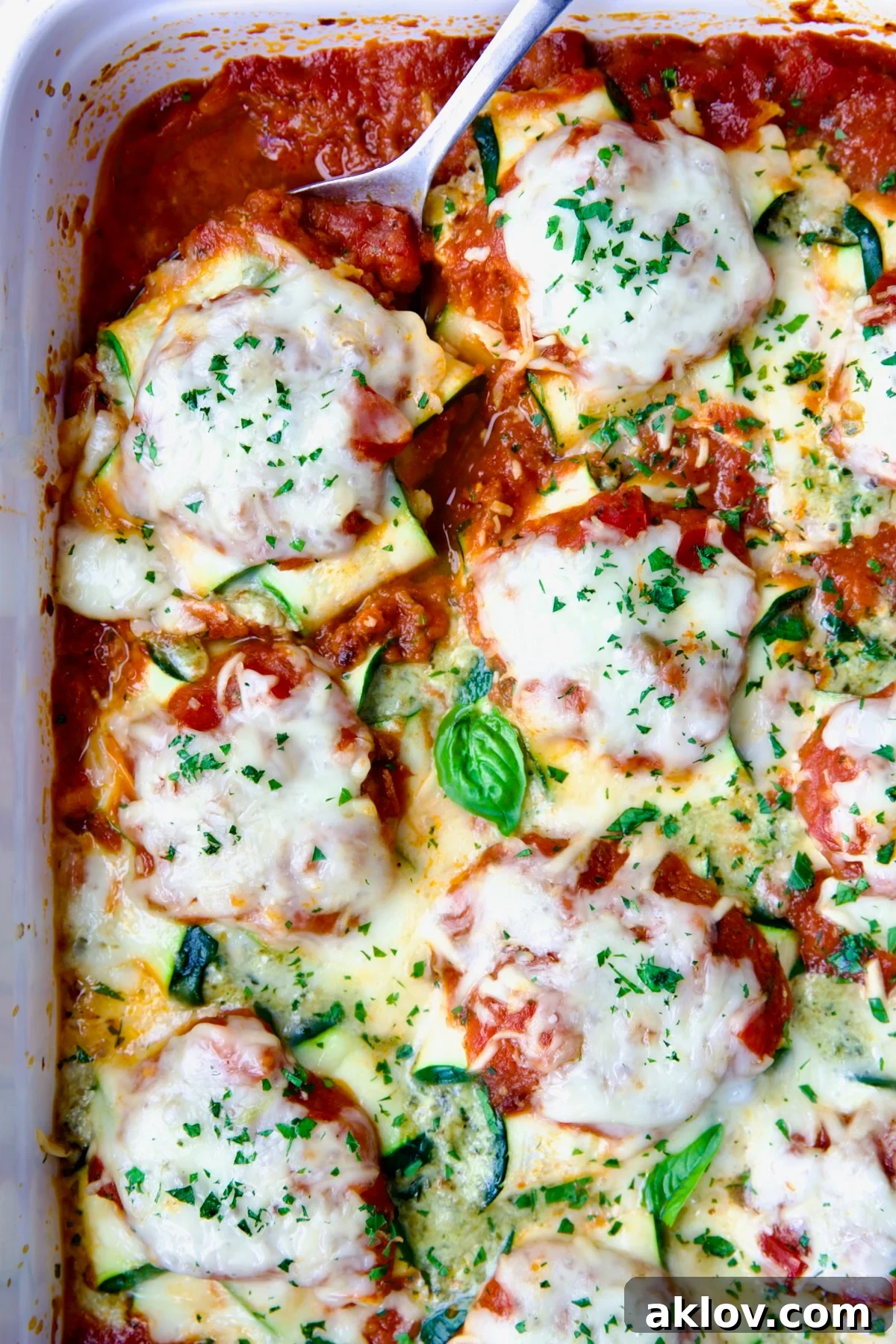 Zucchini Ravioli in white baking dish with serving spoon.