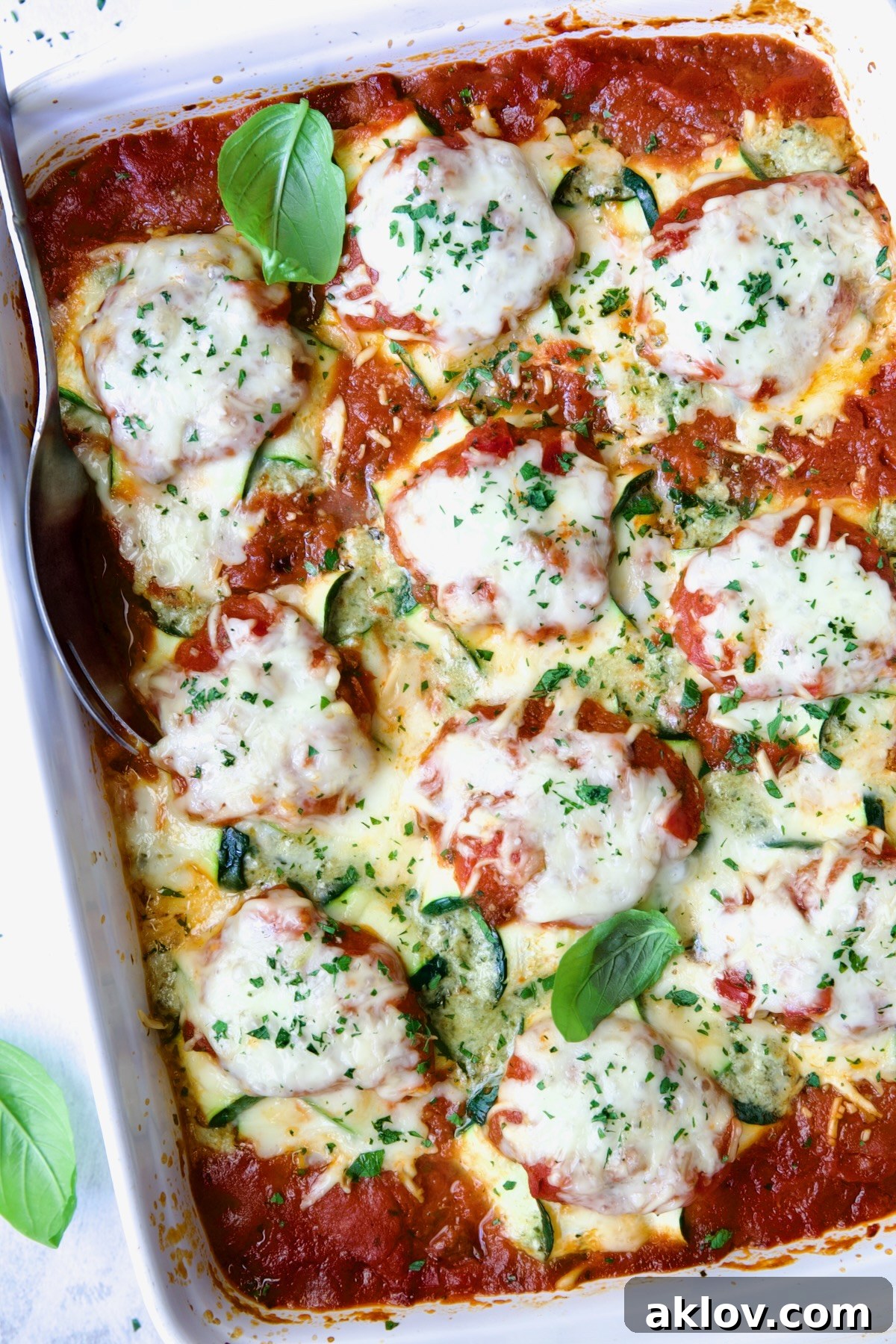 Zucchini Ravioli in white baking dish with serving spoon.