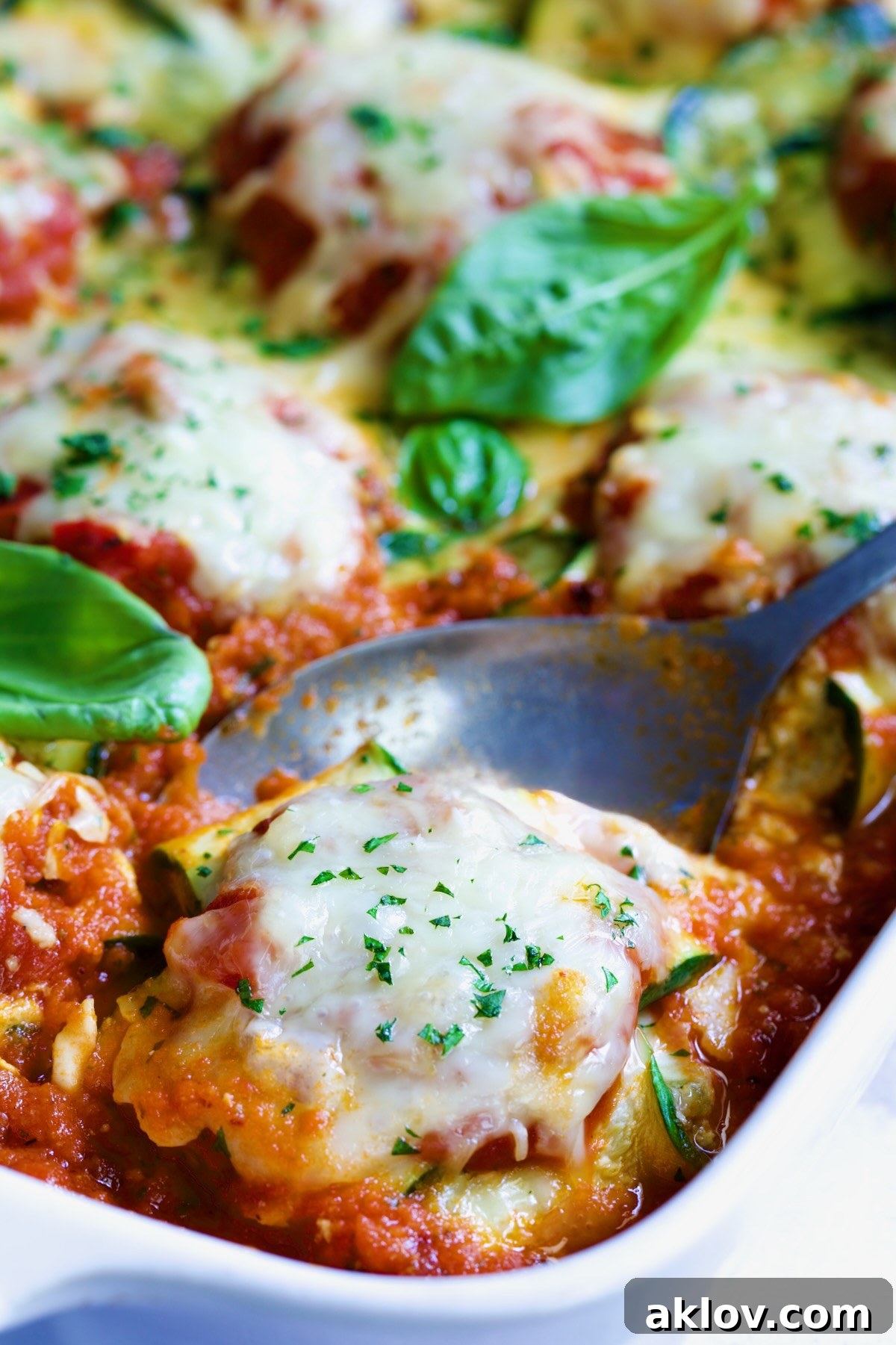Zucchini Ravioli in white baking dish with serving spoon.