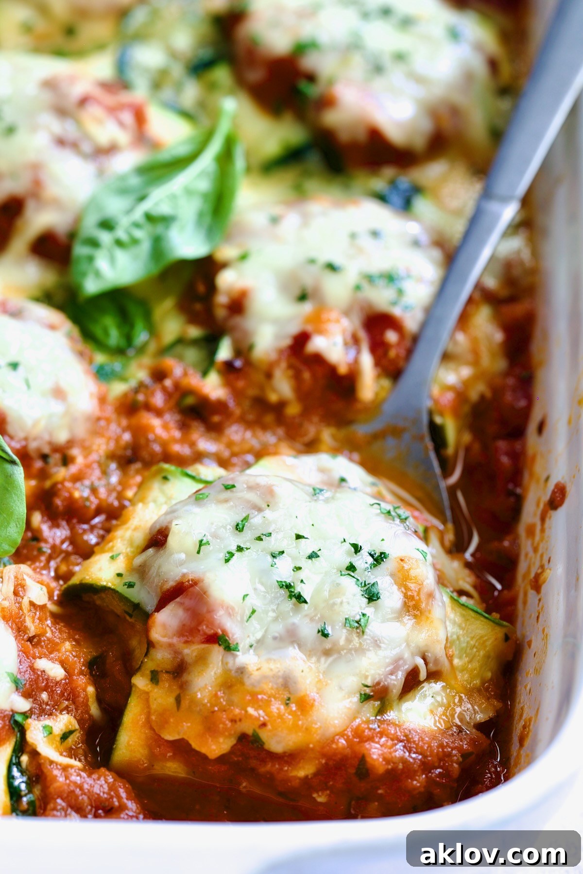 Zucchini Ravioli in white baking dish with serving spoon.