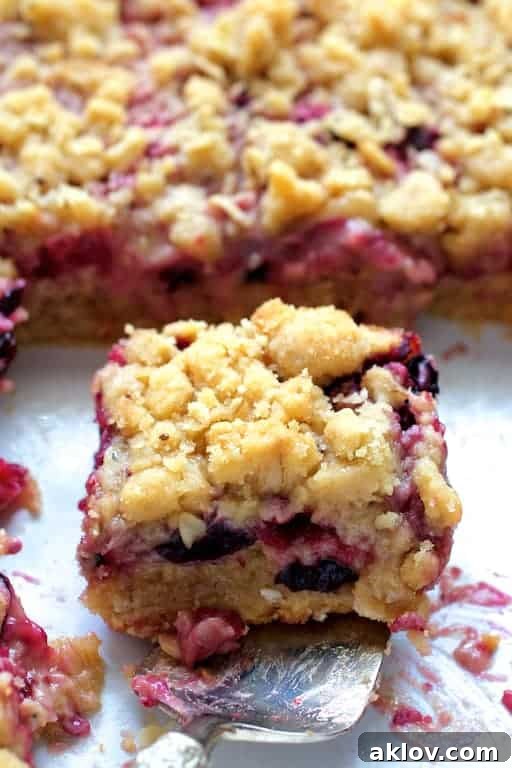 Close-up photo of a Blueberry Crumble Bar on silver pie server about to be removed from white baking dish.