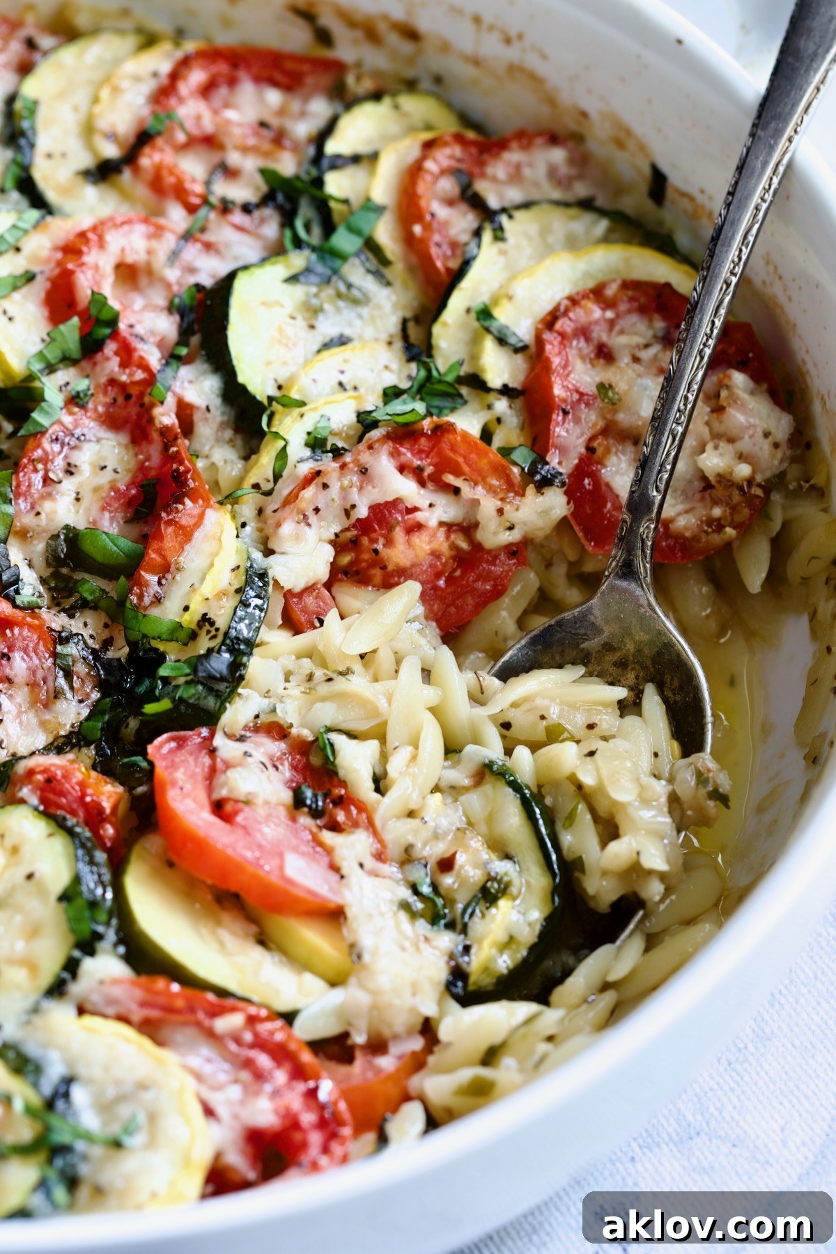 Close-up of Orzo Vegetable Tian in a round white baking dish, showcasing the vibrant vegetable layers.