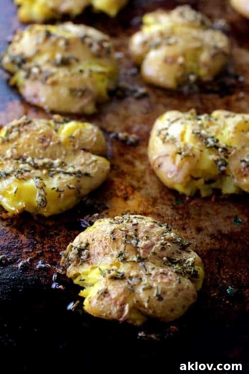 Rosemary Garlic Crushed Potatoes, perfectly golden and crispy, neatly arranged on a baking sheet, fresh from the oven.