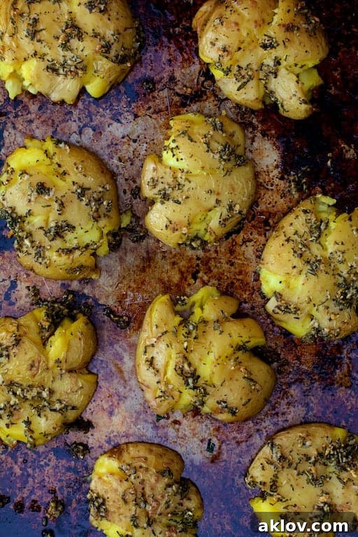 An overhead shot of Rosemary Garlic Crushed Potatoes spread across a baking sheet, each potato distinctively crushed and roasted.