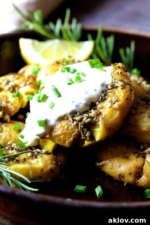 A close-up of a serving of Rosemary Garlic Crushed Potatoes, garnished with fresh chives, showing off their crispy edges and inviting texture, ready to be dipped in aioli.