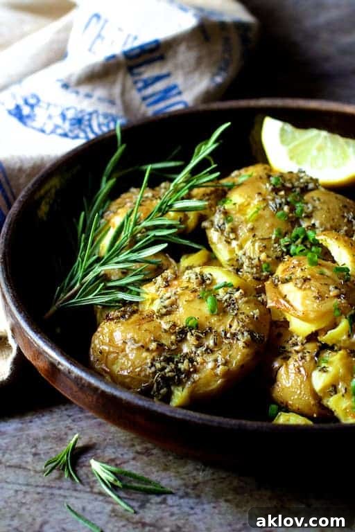Rosemary Garlic Crushed Potatoes in a brown ceramic dish, beautifully garnished with fresh rosemary sprigs, ready to be enjoyed.