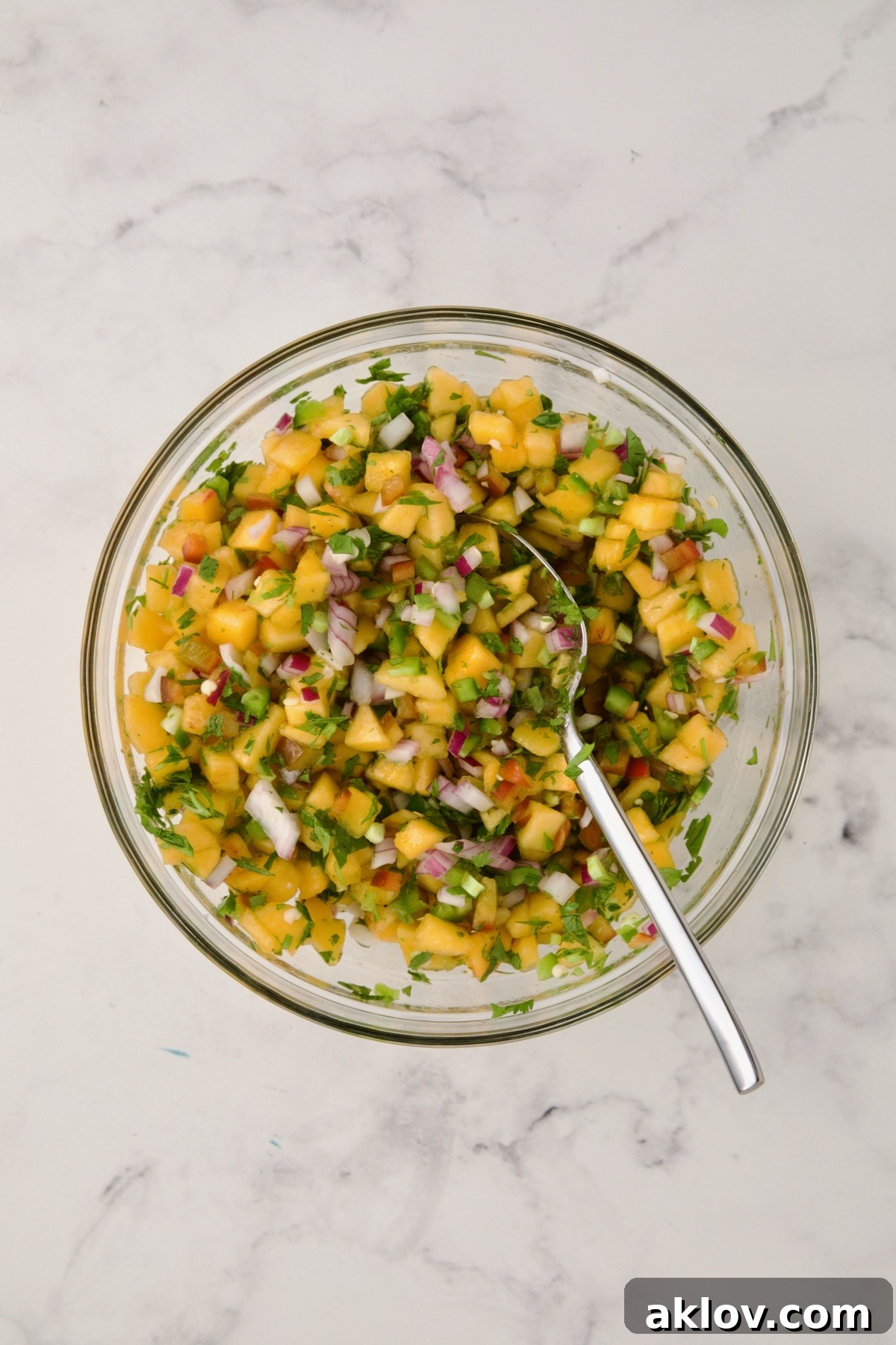The finished peach salsa in a glass bowl, with all ingredients beautifully mixed and ready to serve.