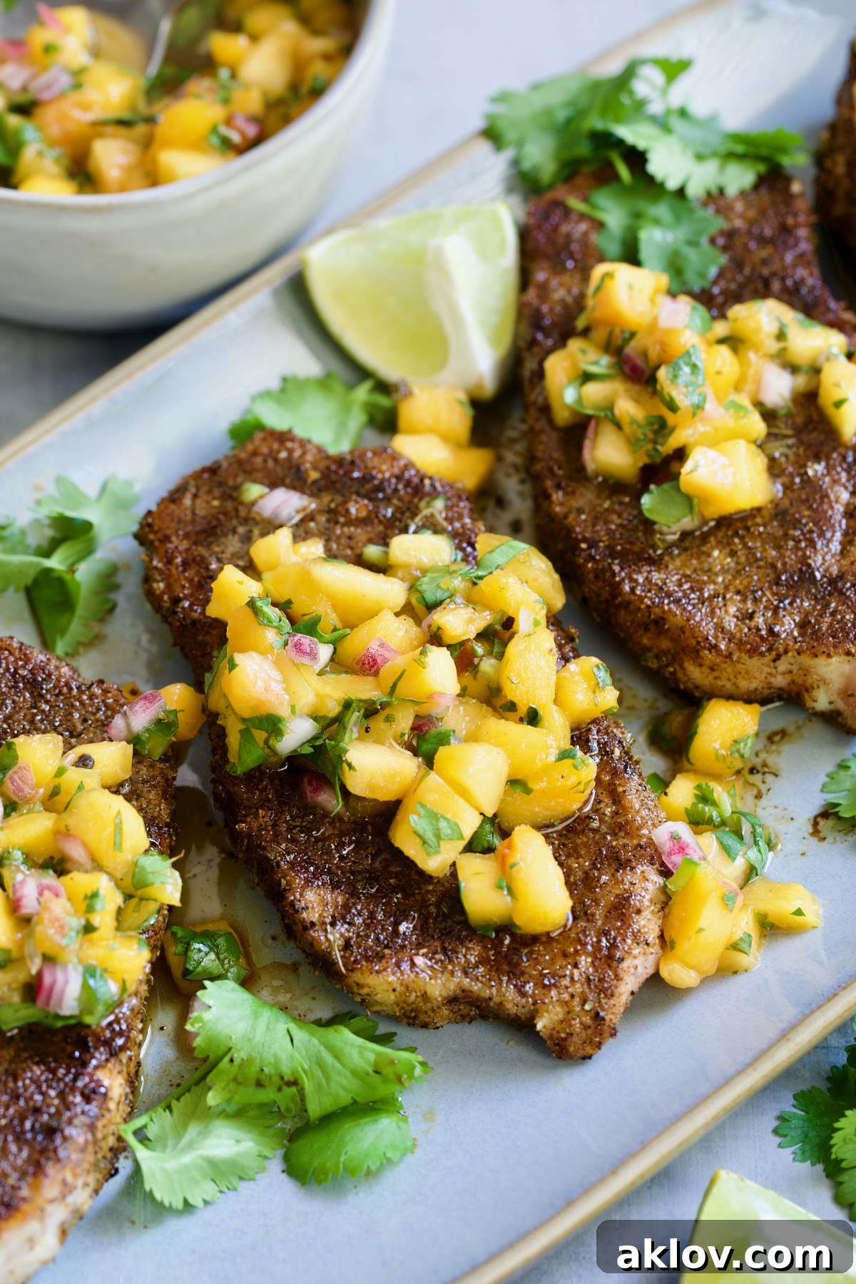 Three Pork Chops with Peach Salsa on oval gray platter.
