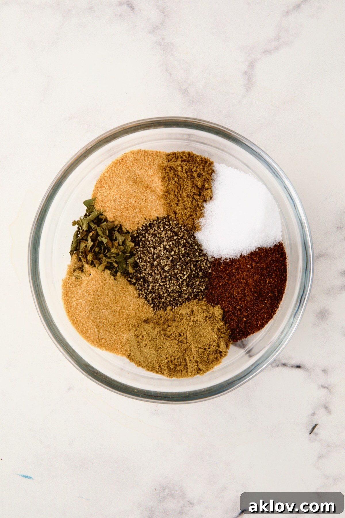 Spices for spice rub in glass bowl before being stirred together.