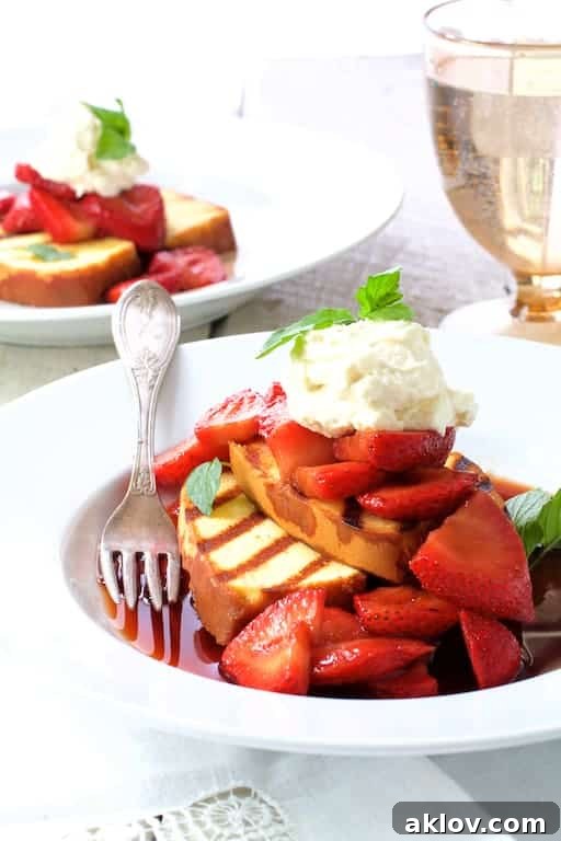 Photo of Grilled Pound Cake with Balsamic Macerated Strawberries and Mascarpone Cream on white plate with water glass in the background.