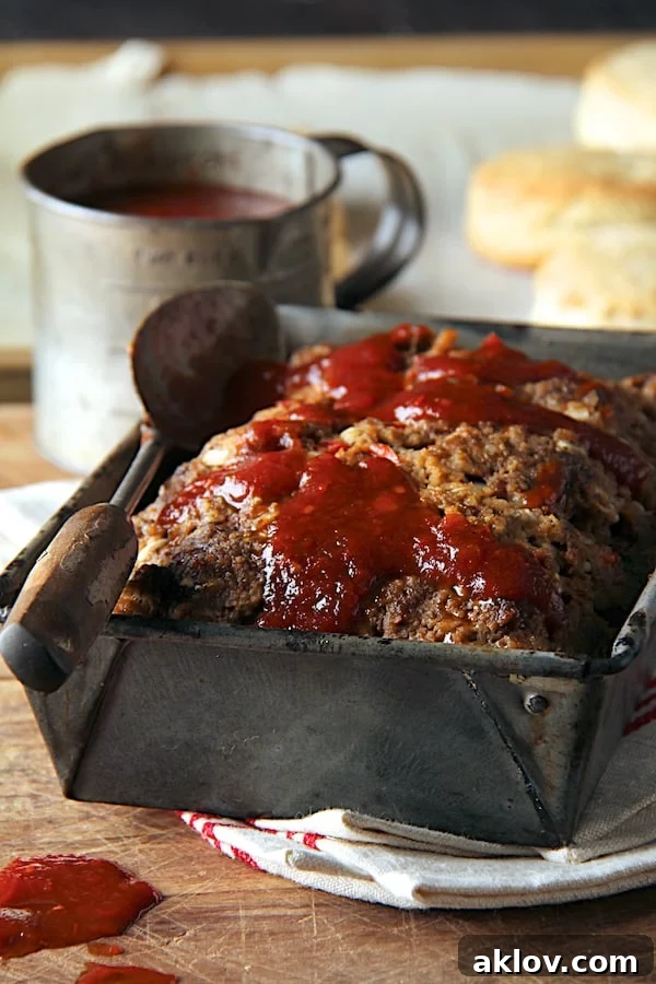 Close-up photo of Chili Glazed Meatloaf in aged metal pan on wood surface.