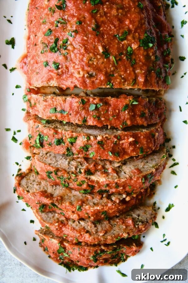 Authentic Italian Meatloaf on a white platter, half-sliced to reveal texture.