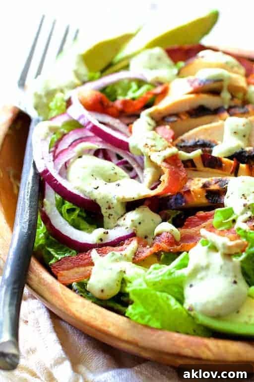 Close-up of the Chicken BLT Salad with Spicy Avocado Ranch Dressing, showing the layered ingredients and a black fork ready to scoop.