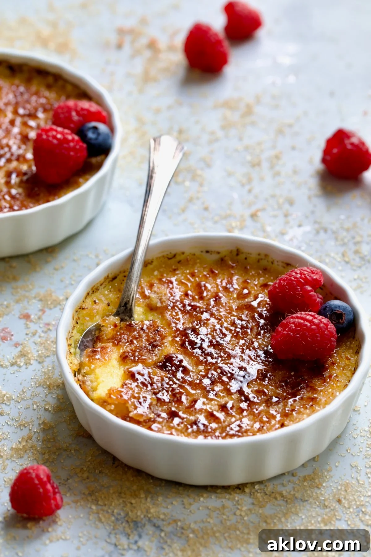 Classic Crème Brûlée for Two garnished with fresh red raspberries and blueberries, ready to be served.