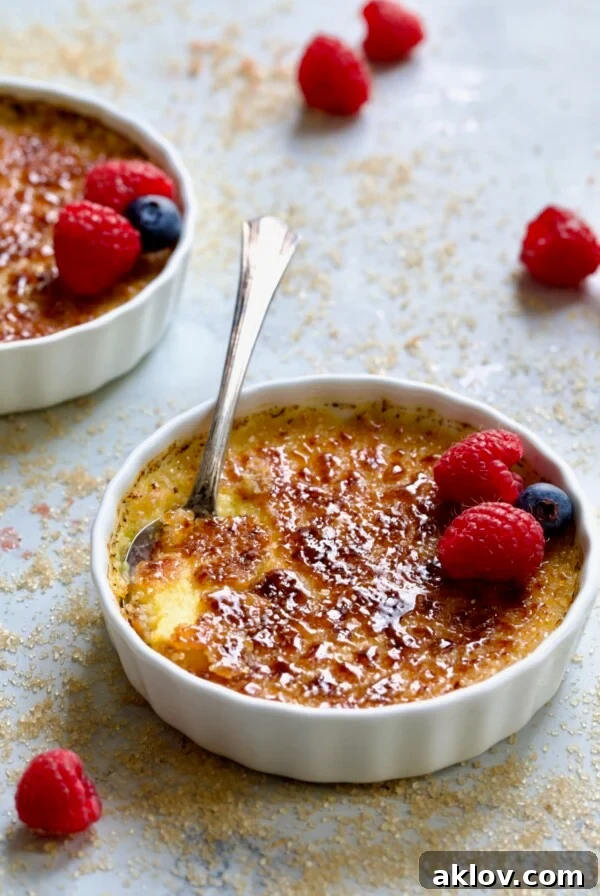 Classic Crème Brûlée for Two garnished with red raspberries and blueberries.