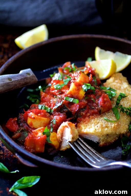 Photo of Chicken Scallopini with Roasted Vegetable Ratatouille in clay dish garnished with lemon wedges with a piece on a fork.