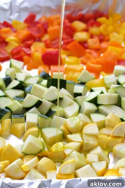 Photo of vegetables for ratatouille on baking sheet being drizzled with olive oil.