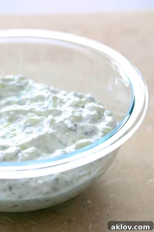 Photo of tzatziki sauce in glass bowl, ready to serve with wraps.