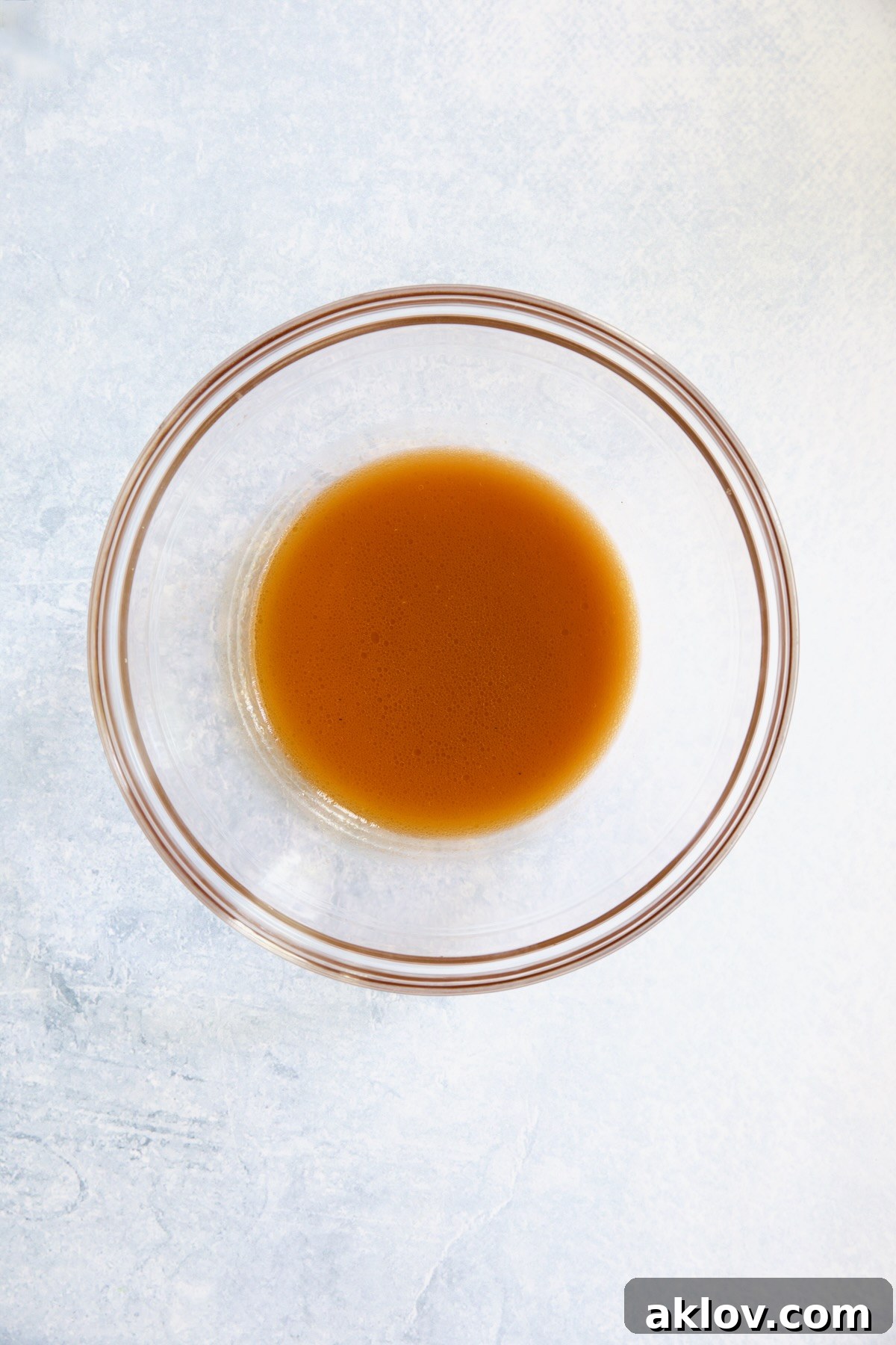 A simple vinaigrette dressing, composed of tomato juices, red wine vinegar, olive oil, garlic, and red pepper flakes, in a glass bowl.