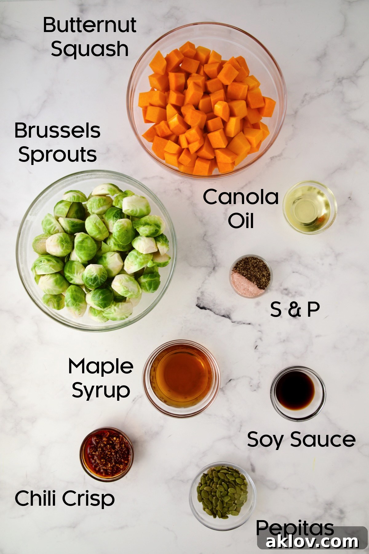 Individual glass bowls showcasing the fresh ingredients required for Maple Chili Crisp Brussels Sprouts and Butternut Squash: vibrant Brussels sprouts, cubed butternut squash, maple syrup, chili crisp, soy sauce, and pepitas.