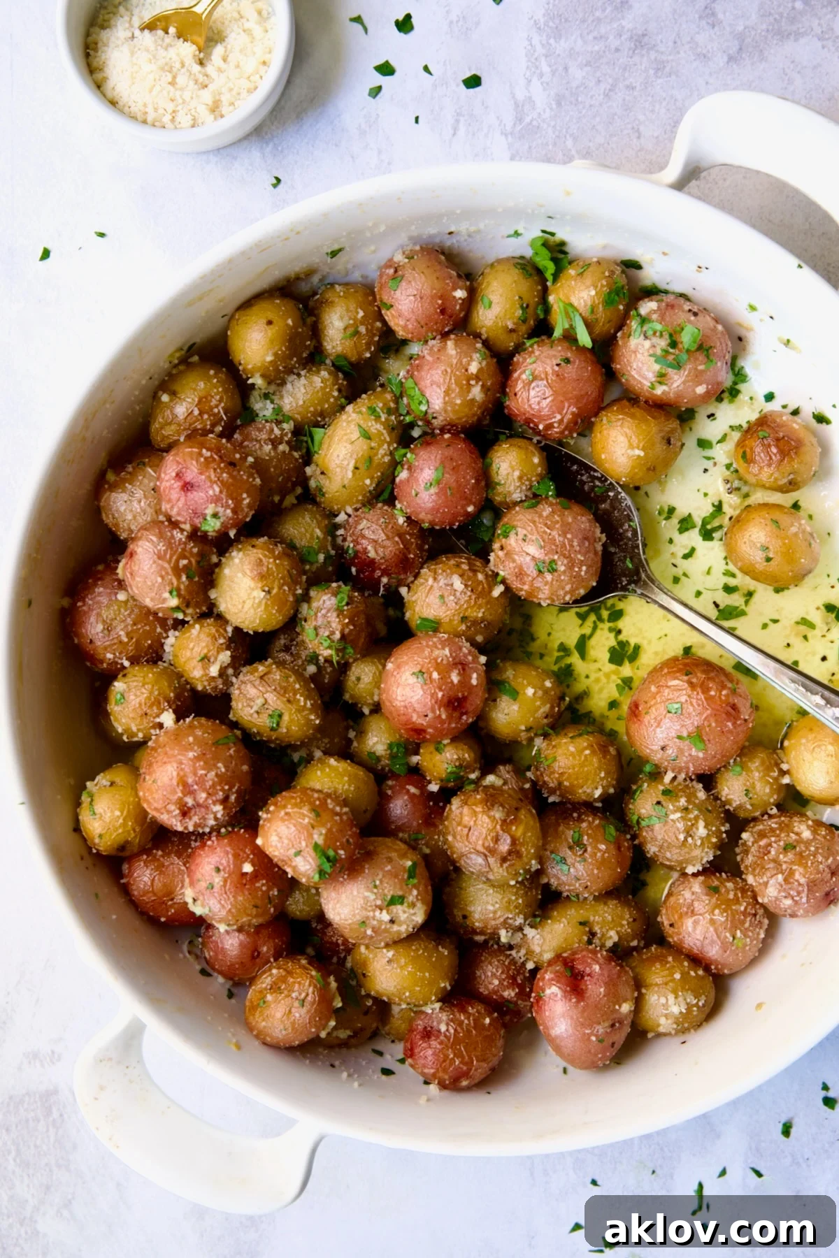Garlic Butter Parmesan Mini Potatoes in round white baking dish with serving spoon.