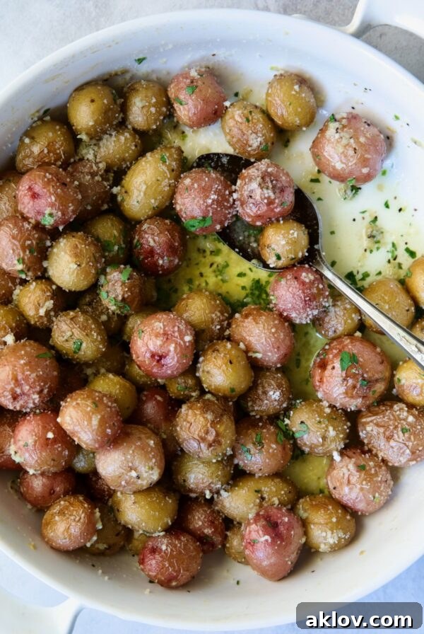 Garlic Butter Parmesan Mini Potatoes in round white baking dish with serving spoon.