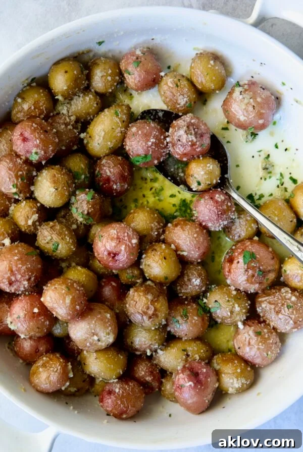 Garlic Butter Parmesan Mini Potatoes in round white baking dish with serving spoon.