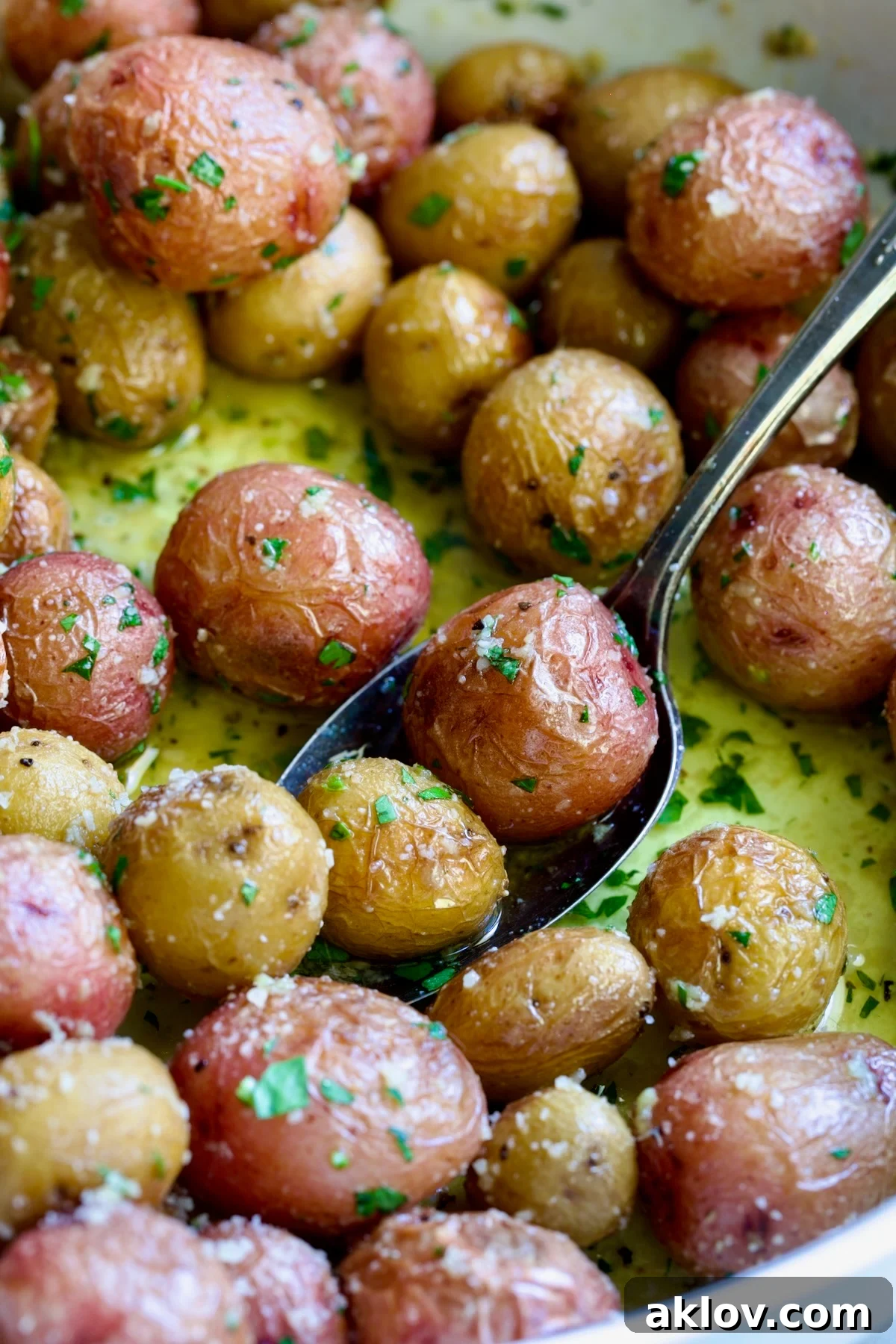 Garlic Butter Parmesan Mini Potatoes in round white baking dish with serving spoon.