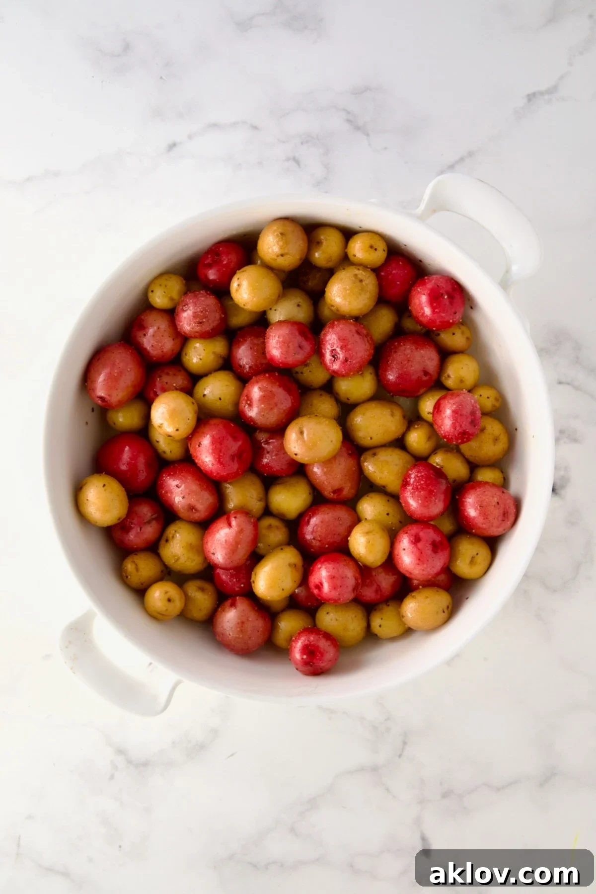 Uncooked mini potatoes in round white baking dish.