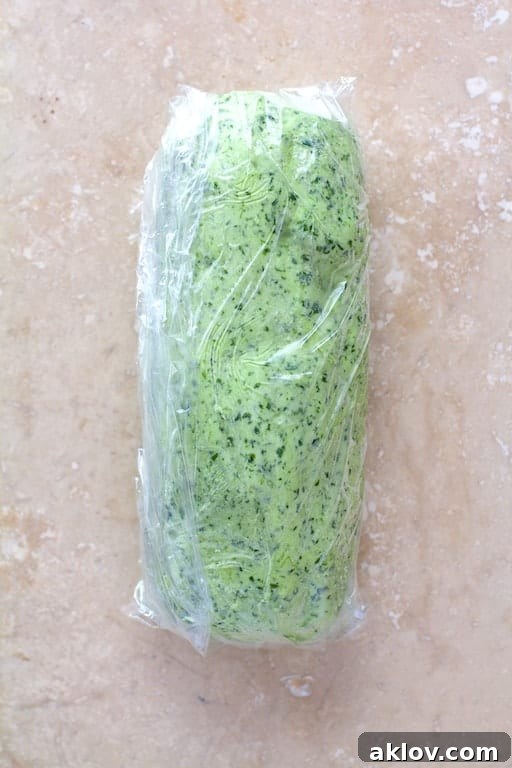Avocado butter meticulously rolled into a neat cylinder within plastic wrap, prepared for freezing and future use.
