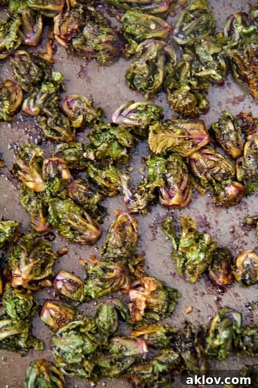 Crispy Balsamic Parmesan Kale Sprouts 4 Roasted kale sprouts spread out on a baking sheet, showing their delicious caramelization.