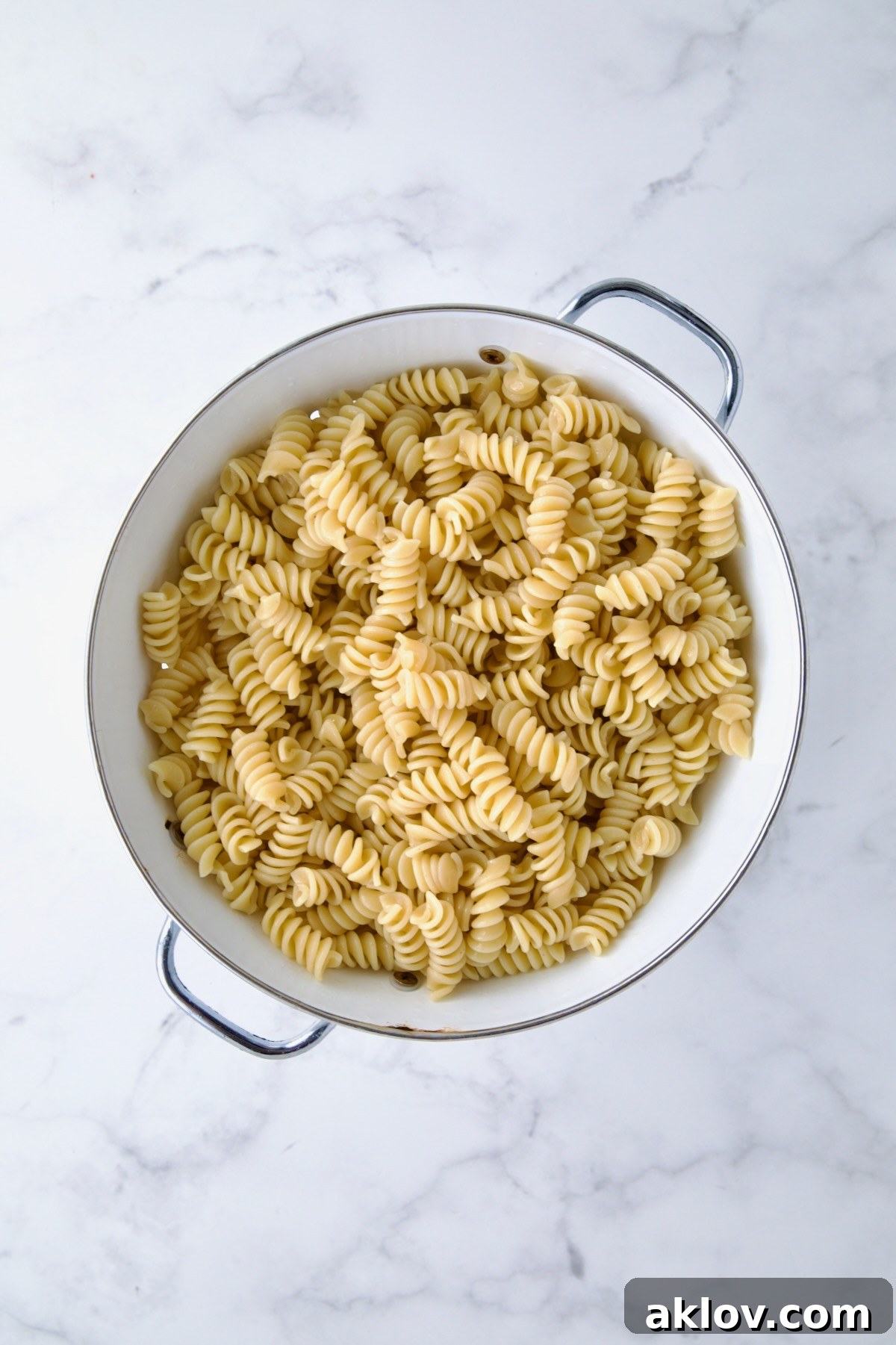 Rotini pasta in white enamel colander.