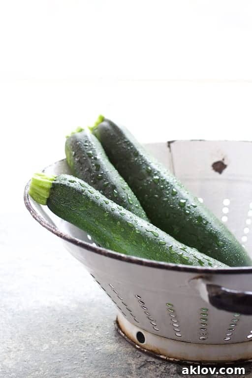 Photo of three freshly washed zucchini in antique white colander.