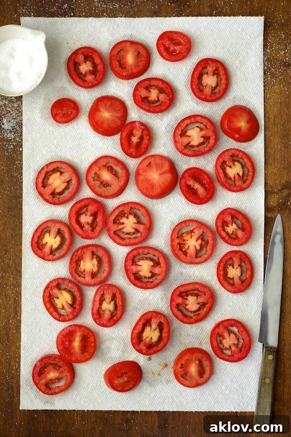 Photo of sliced tomatoes draining on paper towels.