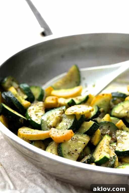 Close-up photo of zucchini and yellow squash being sauteed in stainless steel pan.