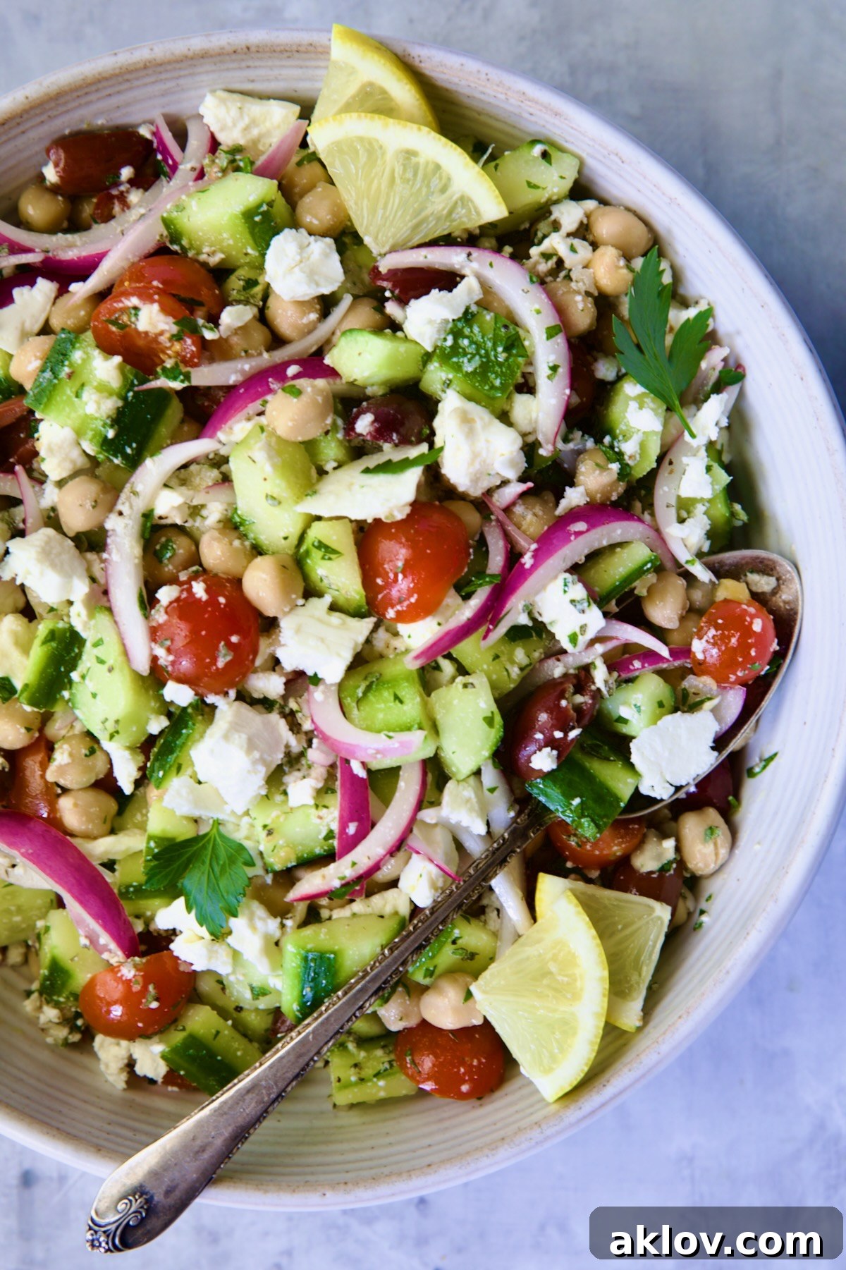 Greek Cucumber Salad in white bowl with serving spoon.