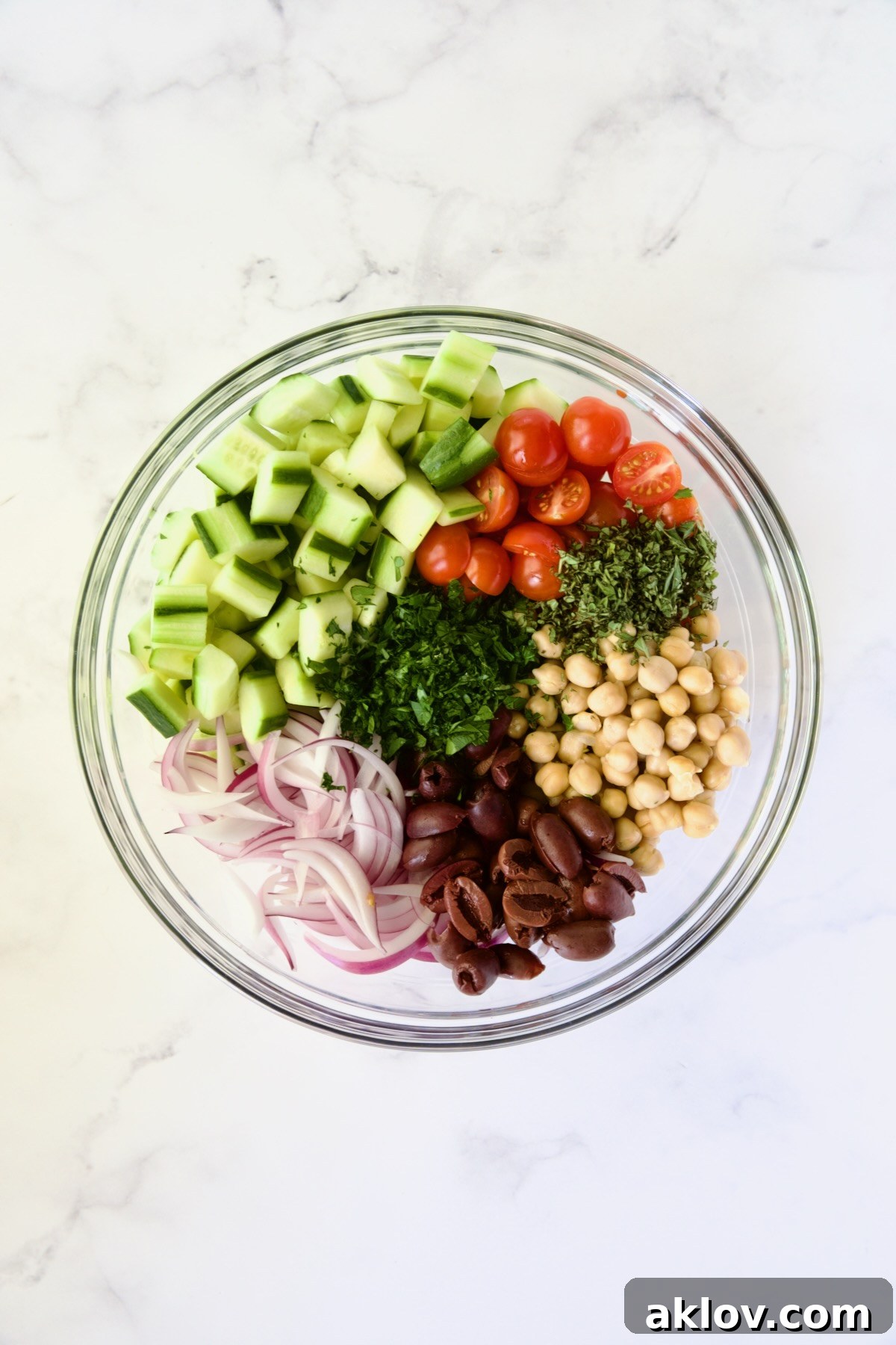 Ingredients for Greek Cucumber Salad in glass bowl before being mixed together.