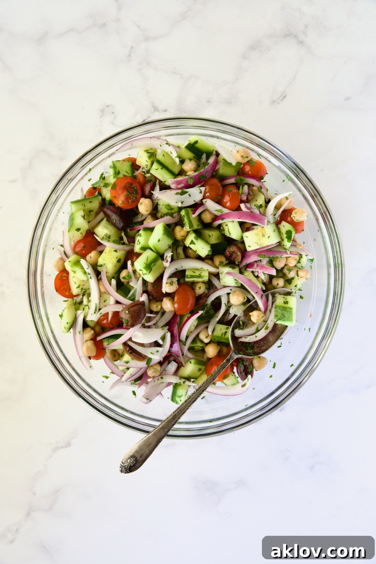 Ingredients for Greek Cucumber Salad in glass bowl after being mixed together.