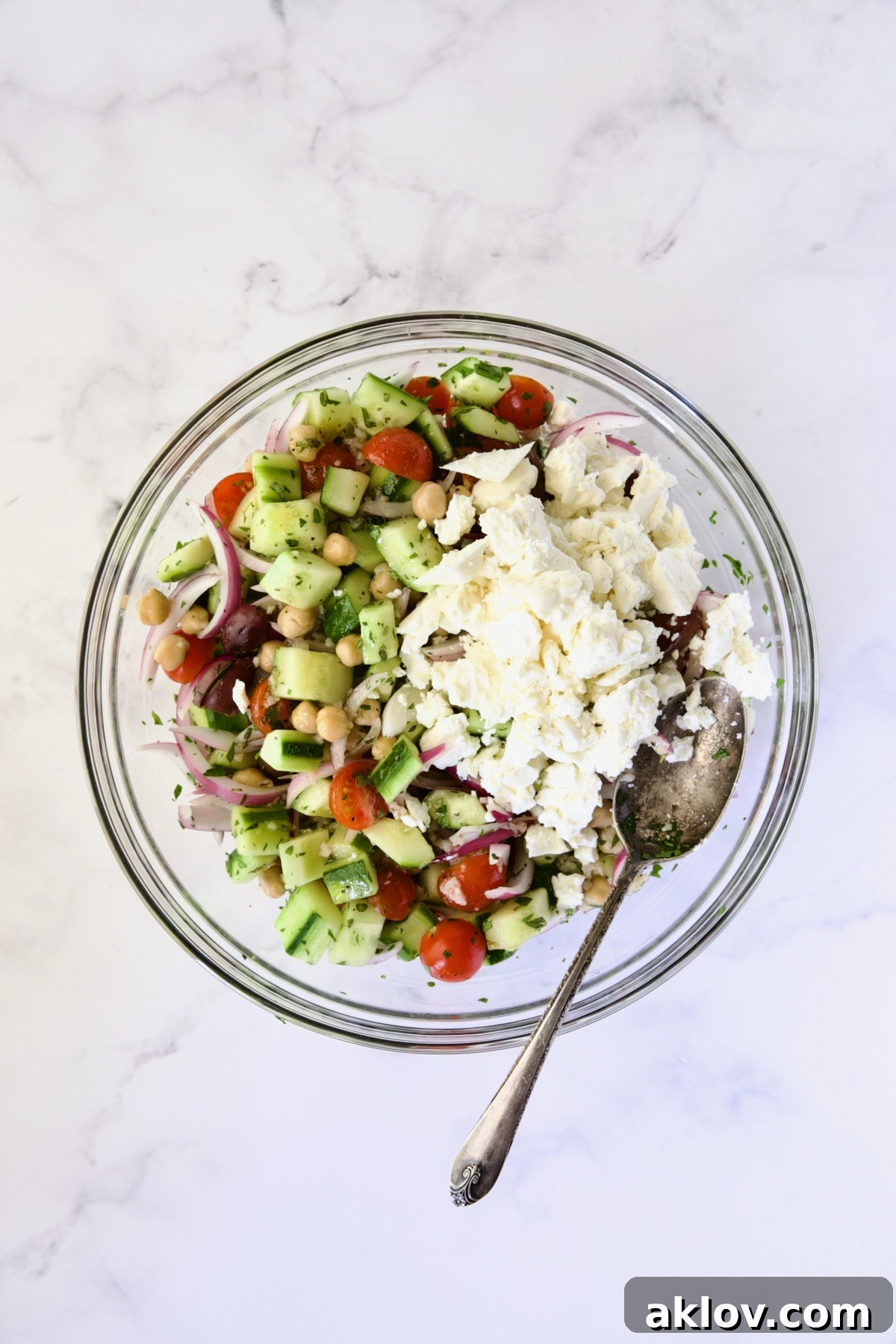 Ingredients for Greek Cucumber Salad in glass bowl after being mixed together with feta cheese added.