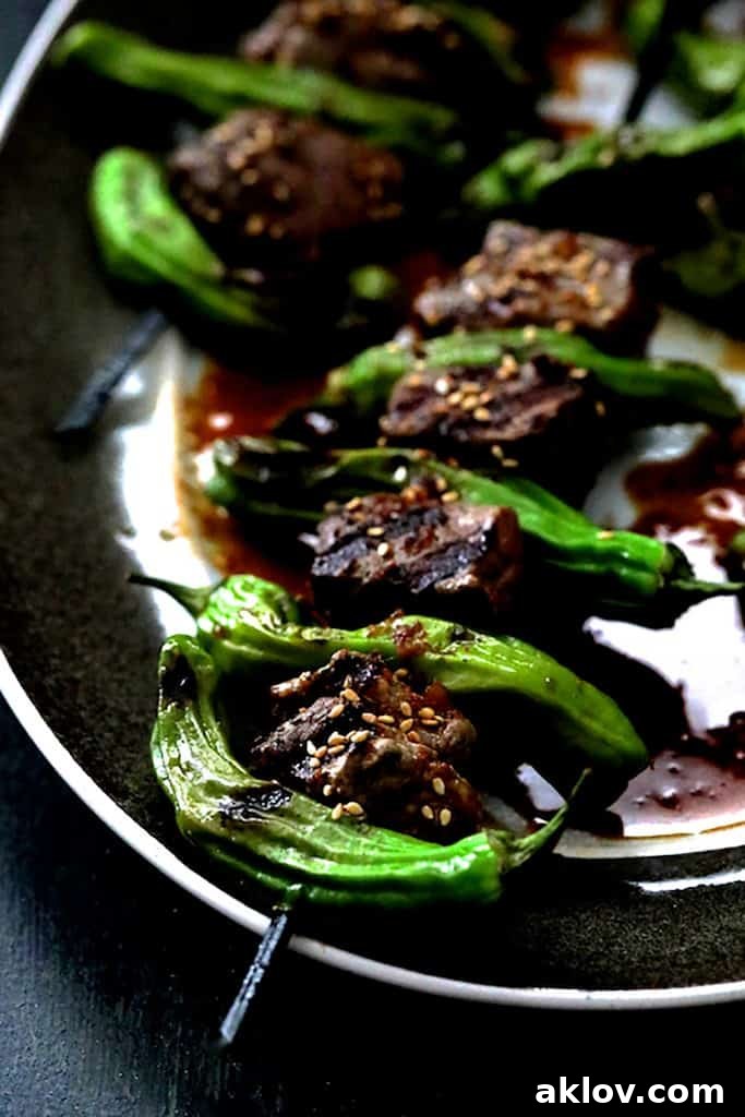 Close-up shot of perfectly grilled Japanese Beef and Shishito Pepper Skewers on a sophisticated gray-rimmed platter.