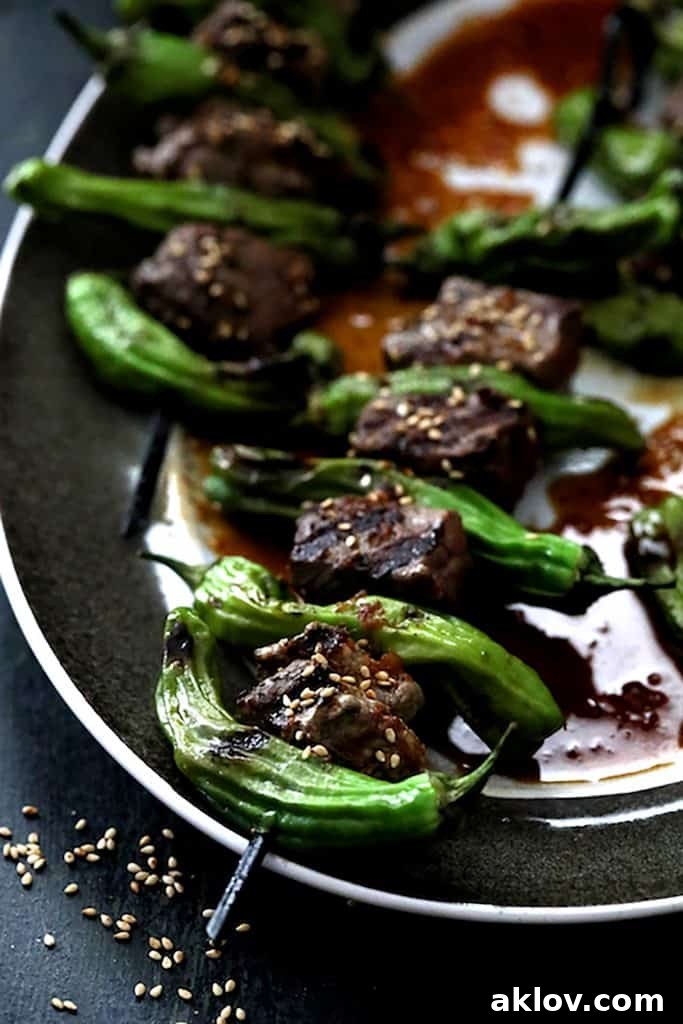 Close-up of Asian Beef and Shishito Pepper Skewers on a platter, beautifully sprinkled with toasted sesame seeds.