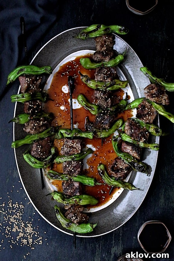 A stunning presentation of Japanese Beef and Shishito Pepper Skewers arranged neatly on an elegant gray-rimmed platter.