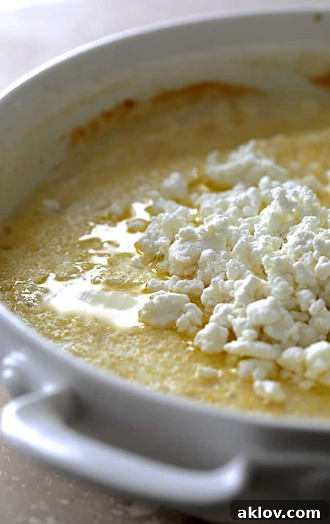 Photo of polenta in white baking dish with goat cheese over the top.