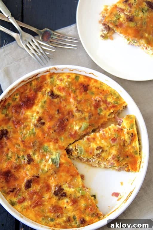 Photo of sliced Crustless Quiche with Sausage, Bacon and Ham with a piece removed onto a plate.