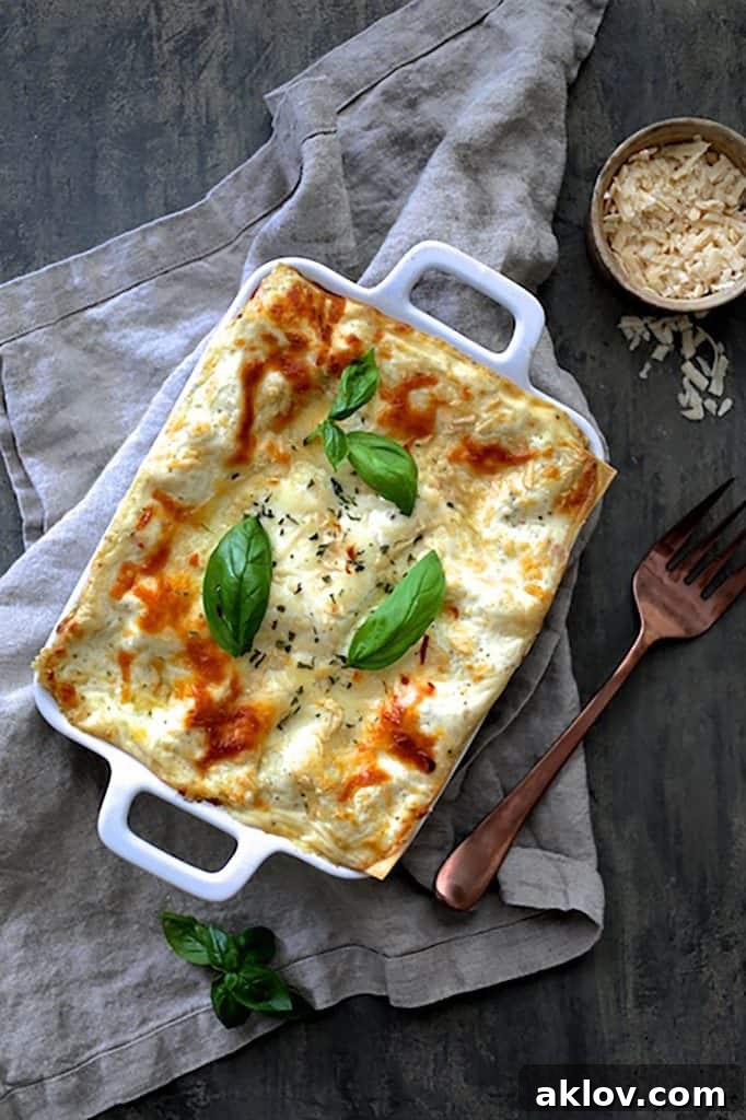 A perfectly sliced portion of Lasagna with Pesto Green Beans and Potatoes, garnished with fresh basil leaves, resting on a gray napkin.