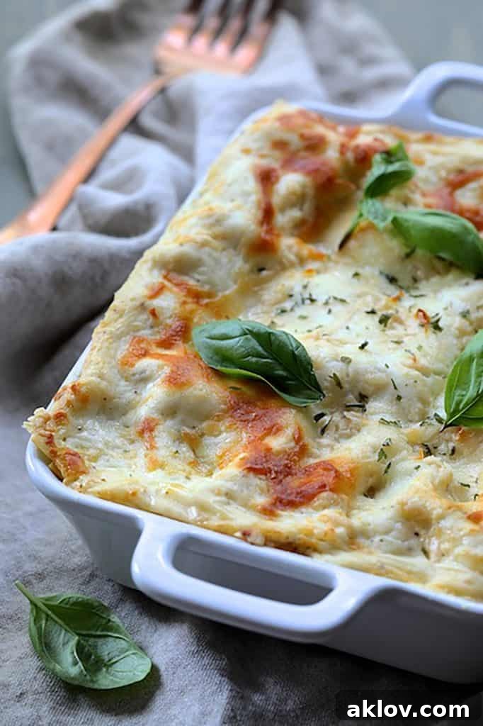 A white baking dish filled with rich Lasagna with Pesto Green Beans and Potatoes, topped with fresh basil, ready to be served.