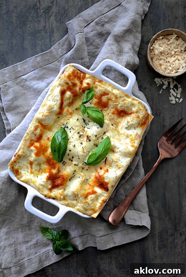 Lasagna with Pesto Green Beans and Potatoes in white baking dish on gray napkin.