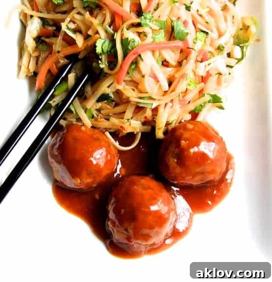 Overhead photo of glazed Hoisin Pork Meatballs with Zesty Rice Noodles and Cabbage and Carrots on a white plate with black chopsticks, ready to eat.